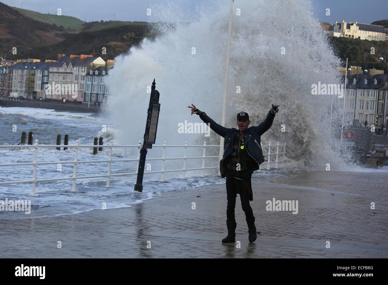 Aberystwyth Wales UK, un stile punk uomo schivato onde enormi durante recenti tempeste invernali. Foto Stock