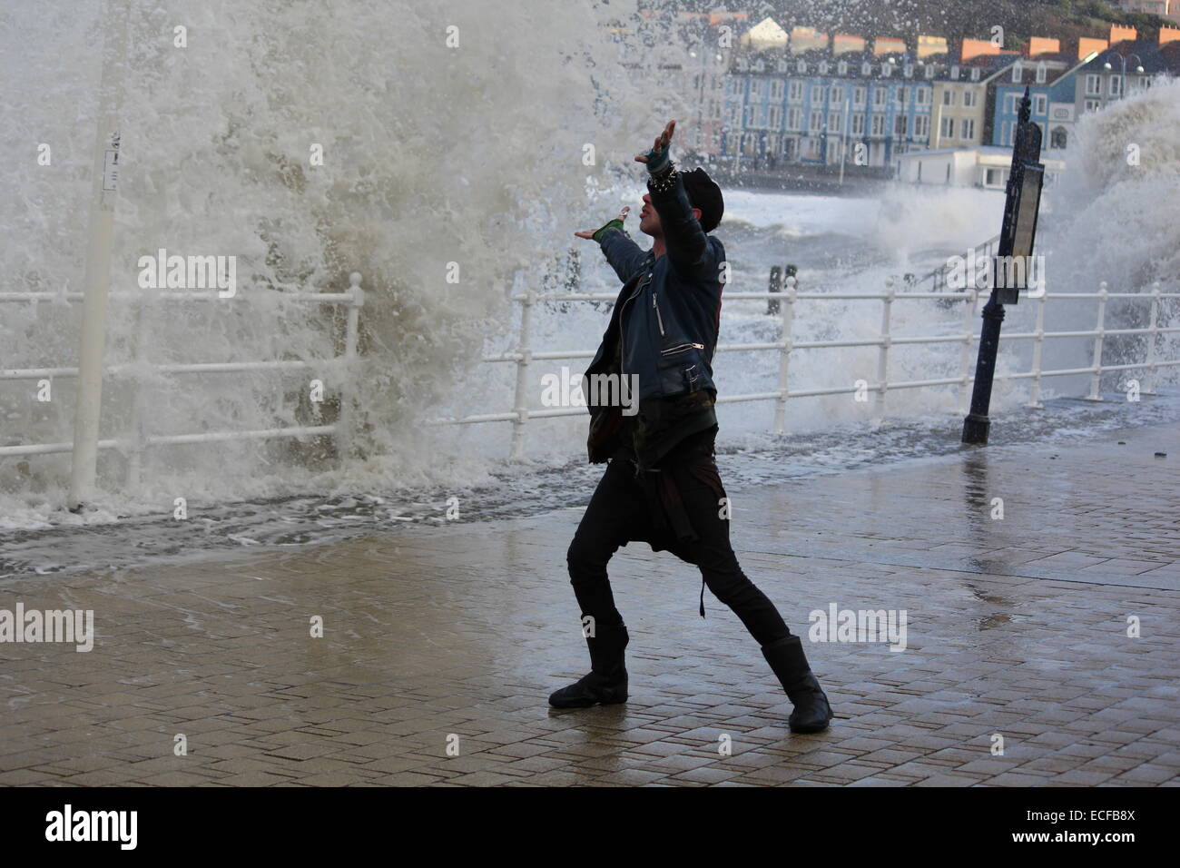 Aberystwyth Wales UK, un stile punk uomo schivato onde enormi durante recenti tempeste invernali . Foto Stock