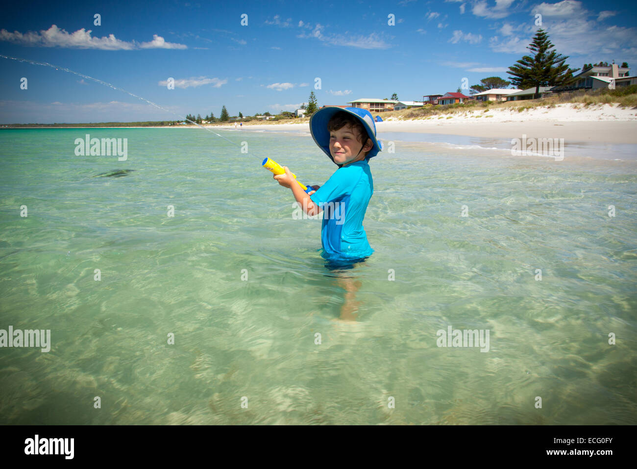 Divertimento estivo - ragazzo giocando in chiaro oceano turchese con una pistola ad acqua Foto Stock