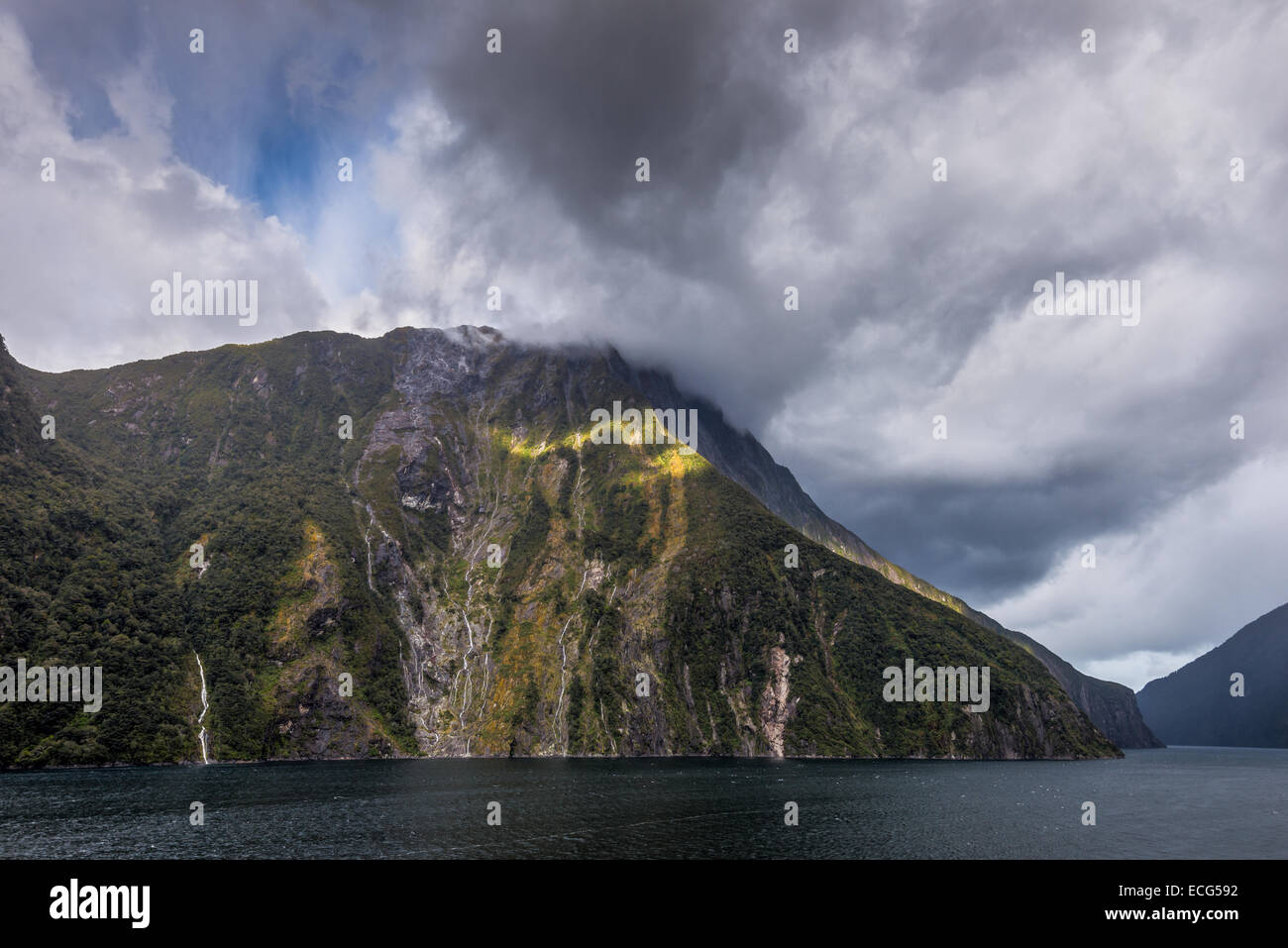 Un stream sunbeam attraverso pesanti cloud a Milford Sound, sull'Isola Sud della Nuova Zelanda Foto Stock