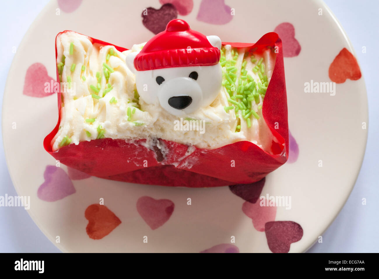 Orso polare indossando hat decorazione sulla torta rossa del velluto impostato sulla piastra di cuore Foto Stock