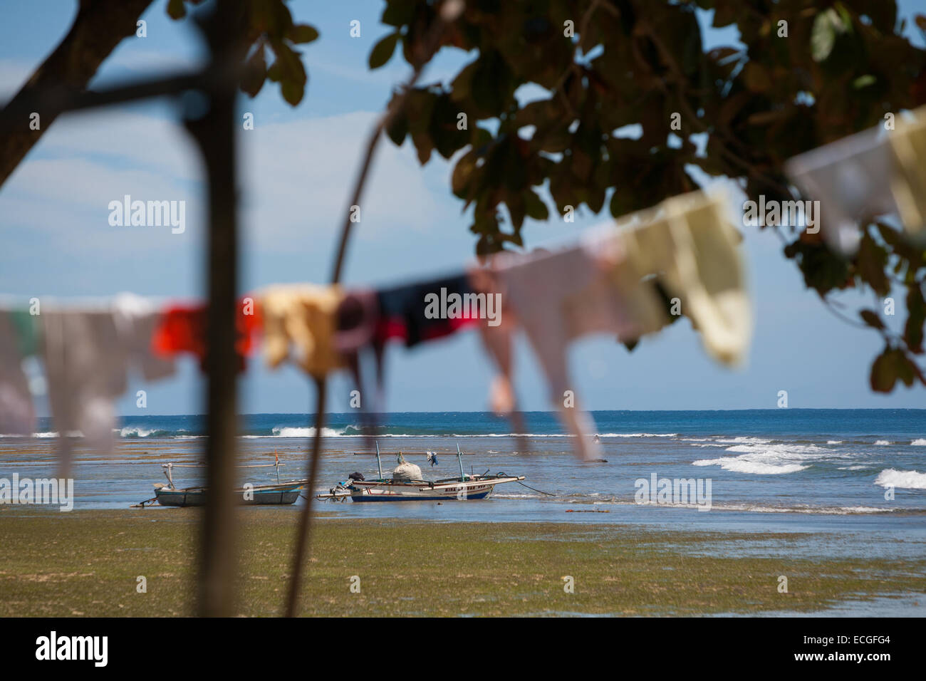Barche da pesca e vestiti di essiccazione del sole sulla spiaggia di Tanjung Setia a Krui, sulla costa occidentale di Lampung, Indonesia. Foto Stock