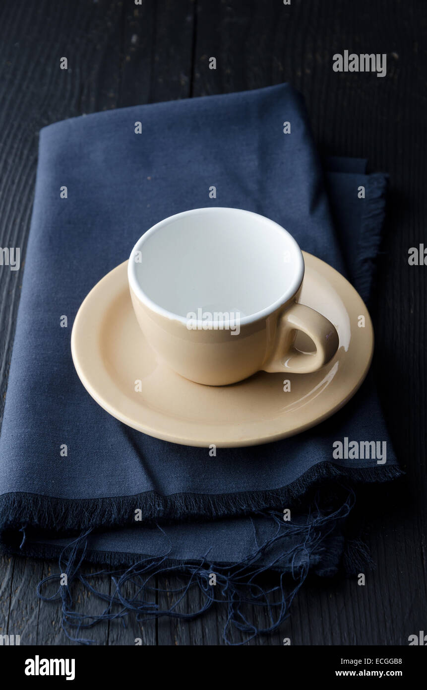 Svuotare tazza da caffè su panno blu scuro, scuro e moody atmosfera Foto Stock