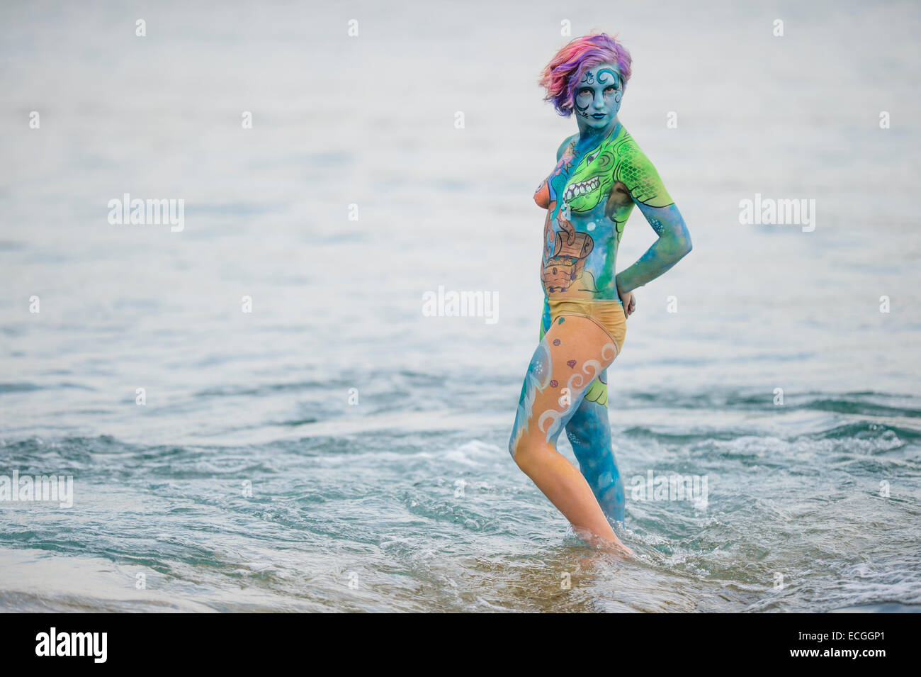 Una giovane donna ragazza modello con il suo corpo verniciato con marino subacqueo animali e creature fantastiche, in piedi all'aperto in un mare calmo acqua, REGNO UNITO Foto Stock