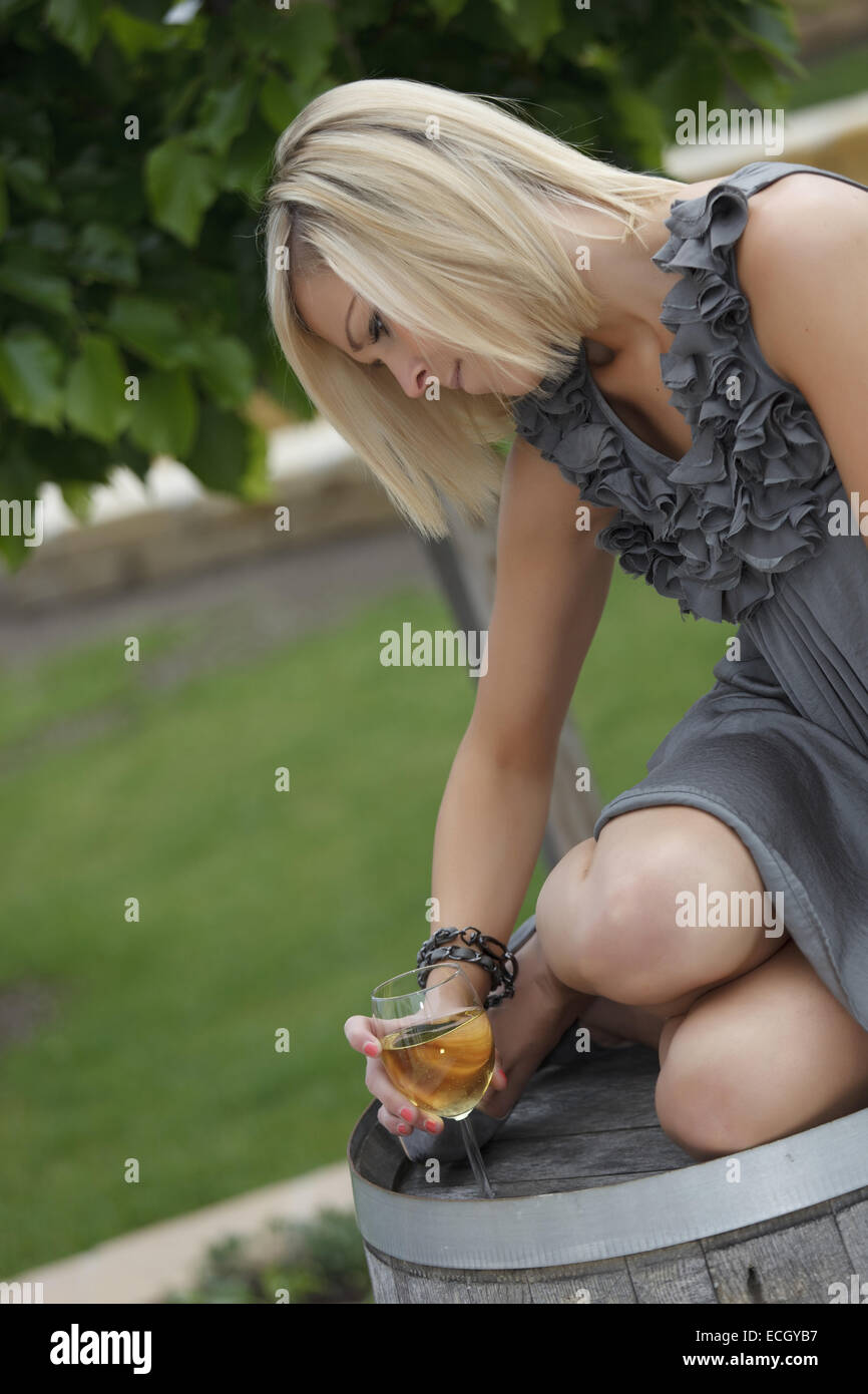 Bella giovane donna con un bicchiere di vino seduti sulla botte di vino  Foto stock - Alamy