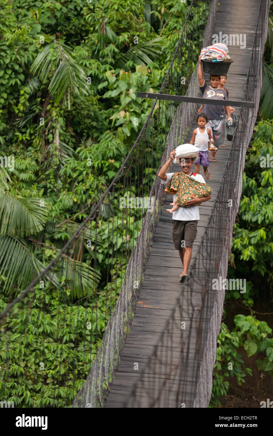 Abitanti del villaggio che camminano attraverso un ponte sospeso a Tangkahan, Langkat, Sumatra settentrionale, Indonesia. Foto Stock
