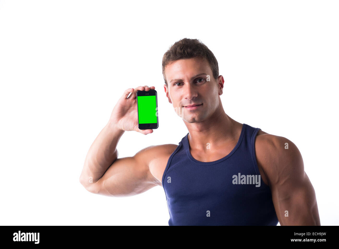Attraente muscolare sorridente giovane uomo che mostra il suo telefono cellulare è vuota dello schermo verde, isolato su bianco Foto Stock