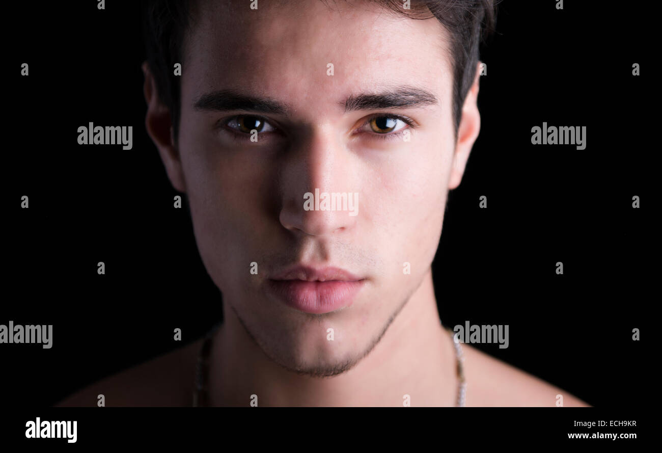 Closeup headshot del bel giovane, capelli scuri e gli occhi castani, isolato su nero Foto Stock