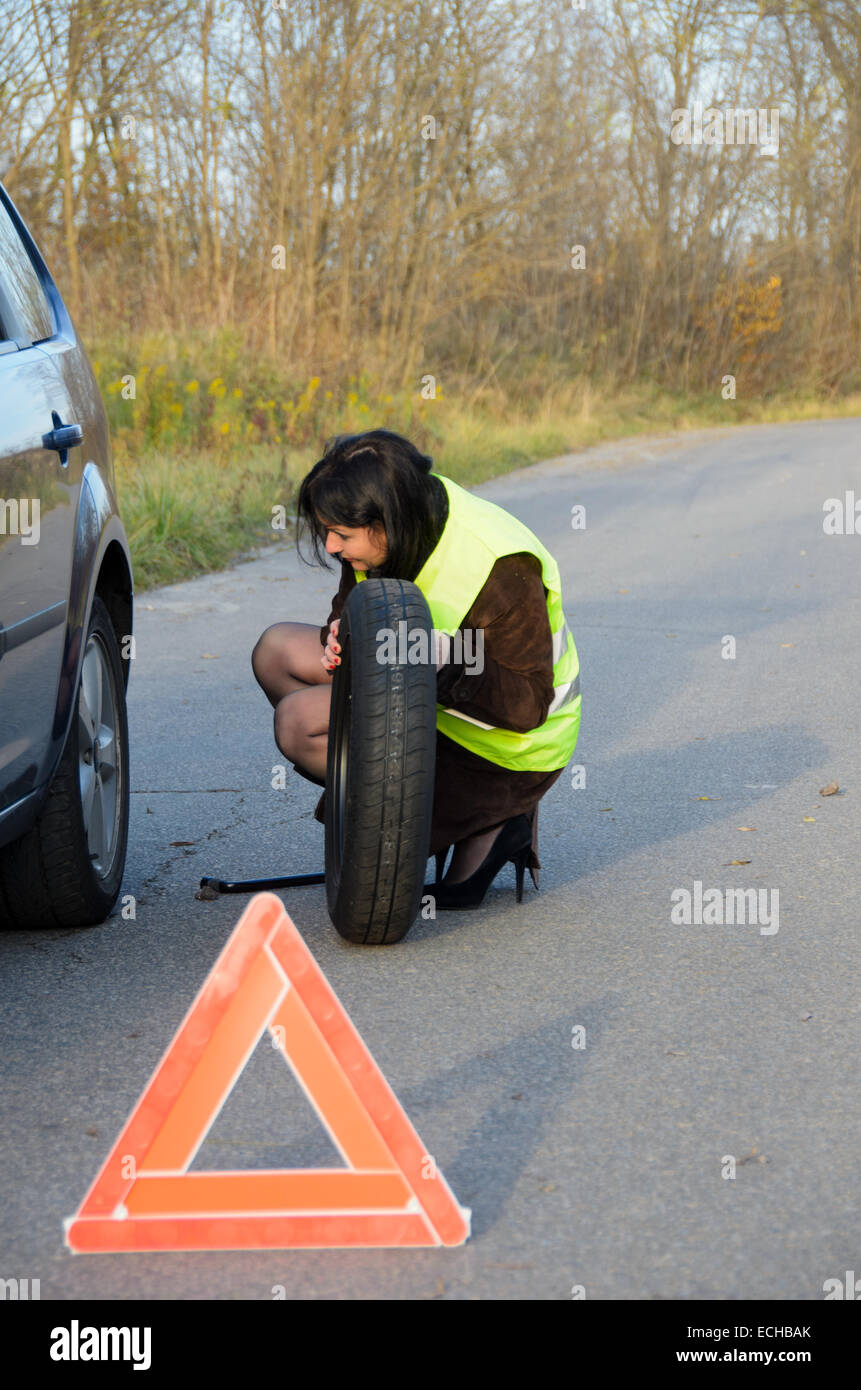 Una foto di una donna con una ruota rotto in auto Foto Stock