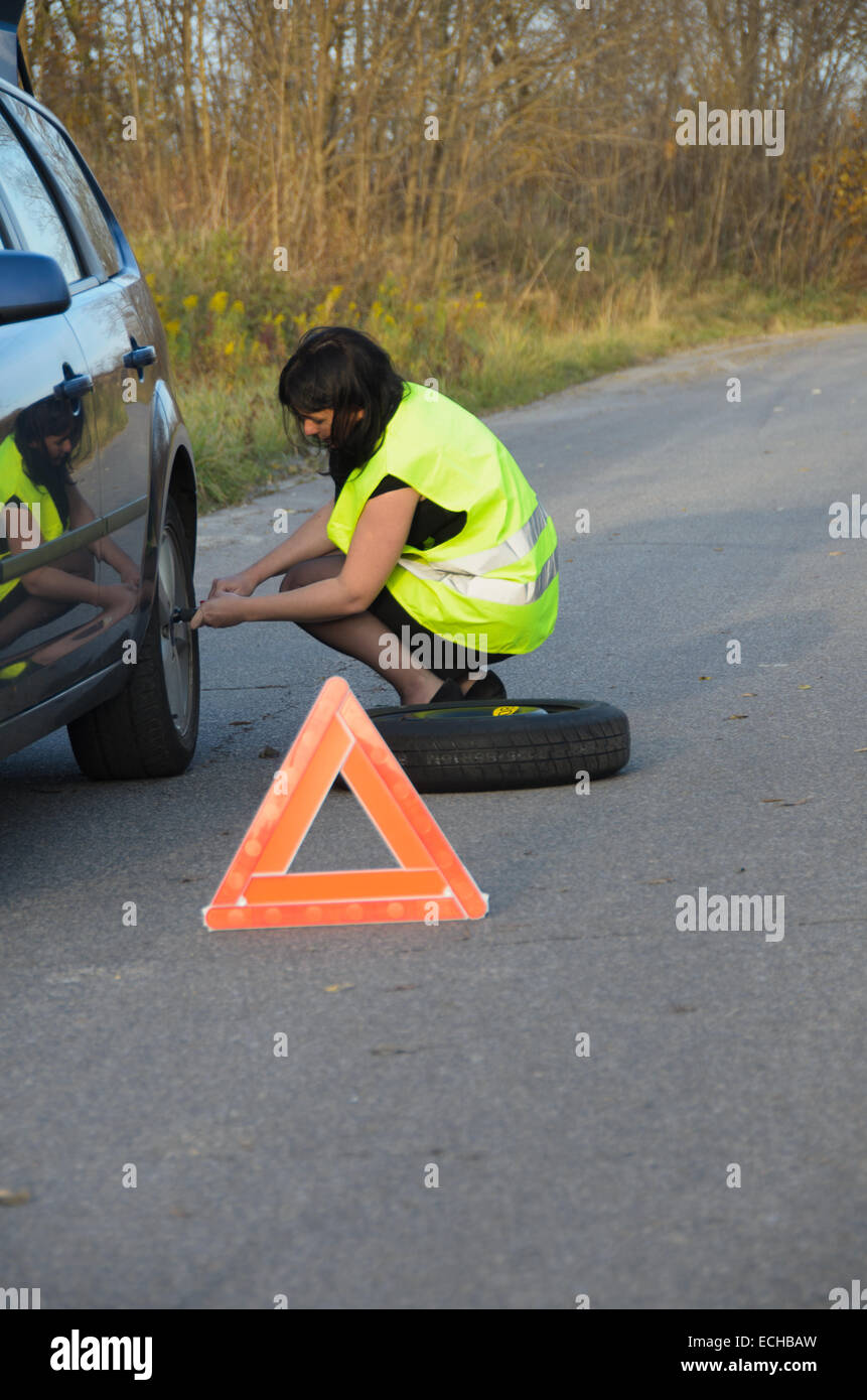 Una foto di una donna con una ruota rotto in auto Foto Stock