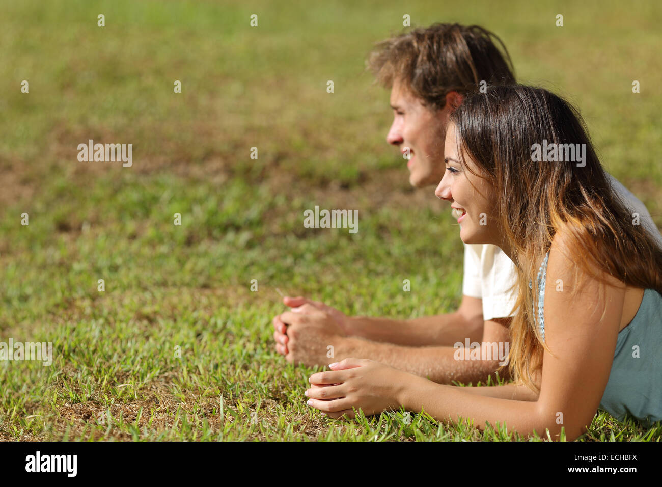 Profilo di un giovane sdraiati sull'erba e guardando lontano con uno sfondo verde Foto Stock