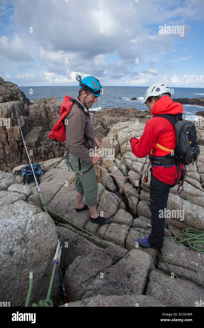 Arrampicatori preparando le corde per una traversata tirolese per accedere a una pila di mare. Gweedore, County Donegal, Irlanda. Foto Stock