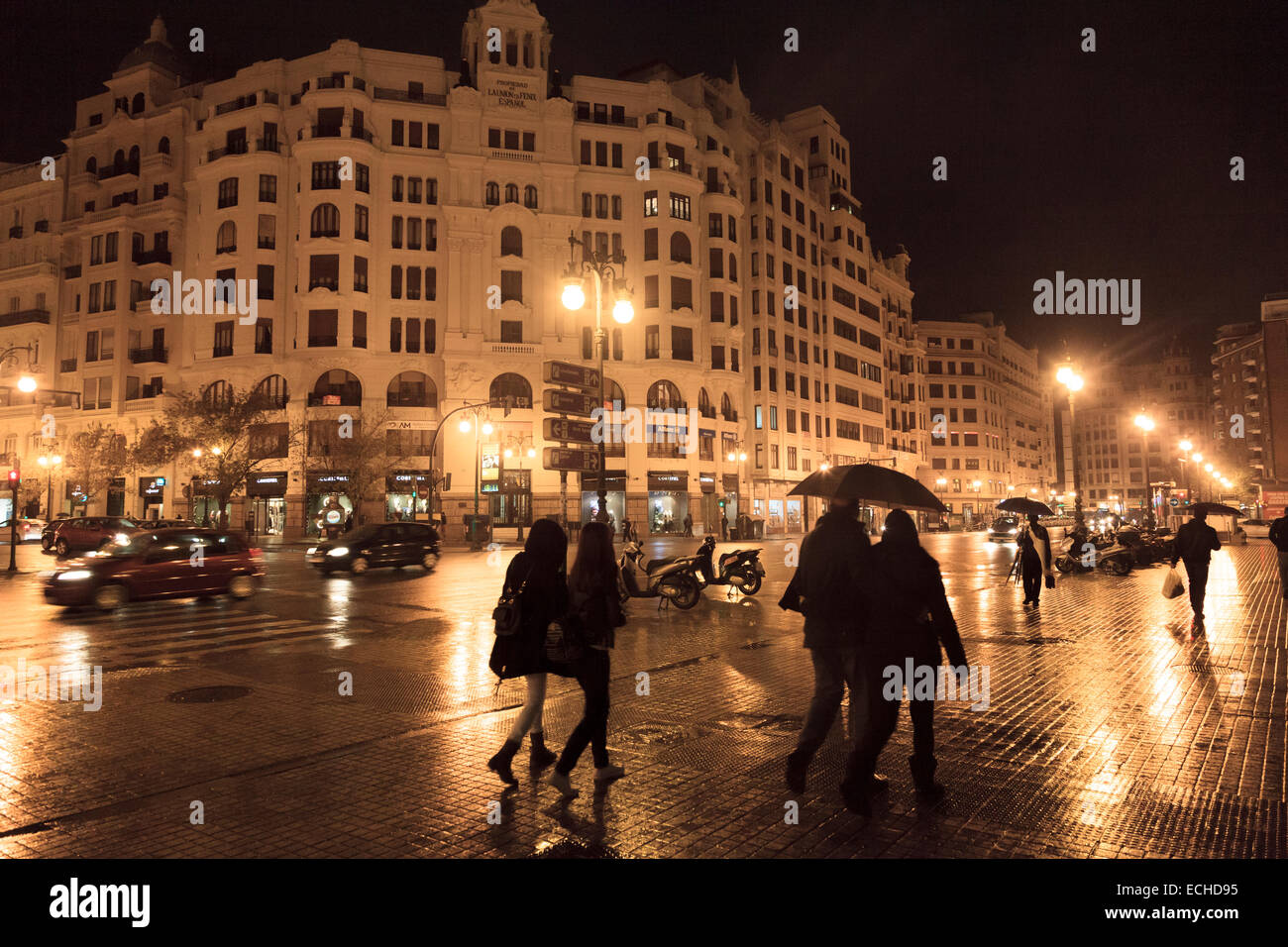 Le persone sotto gli ombrelloni su una notte piovosa sulle strade di Valencia in Spagna Foto Stock