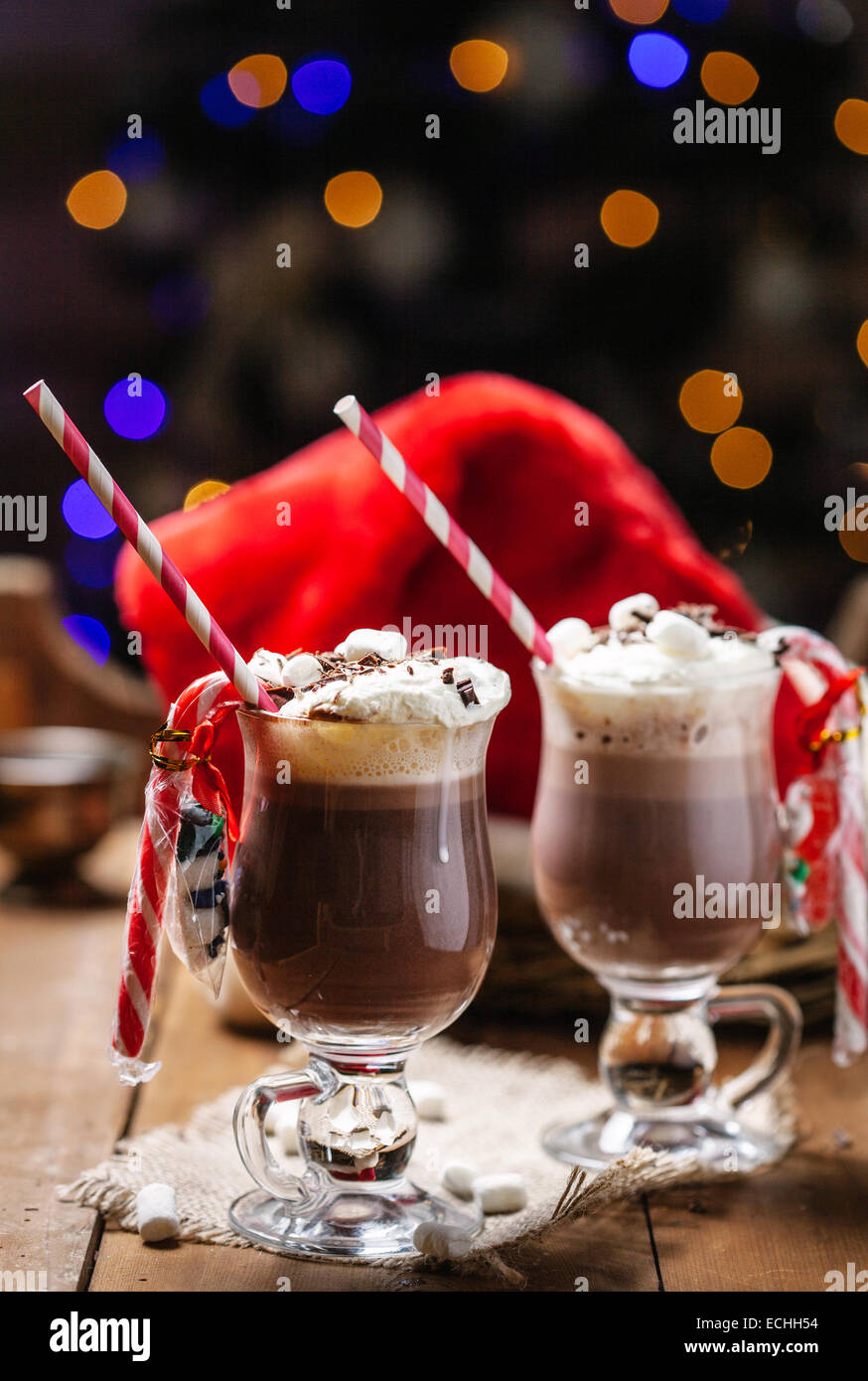 Due bicchieri di cioccolata calda con panna e marshmallow sedersi accanto a un albero di Natale. Foto Stock