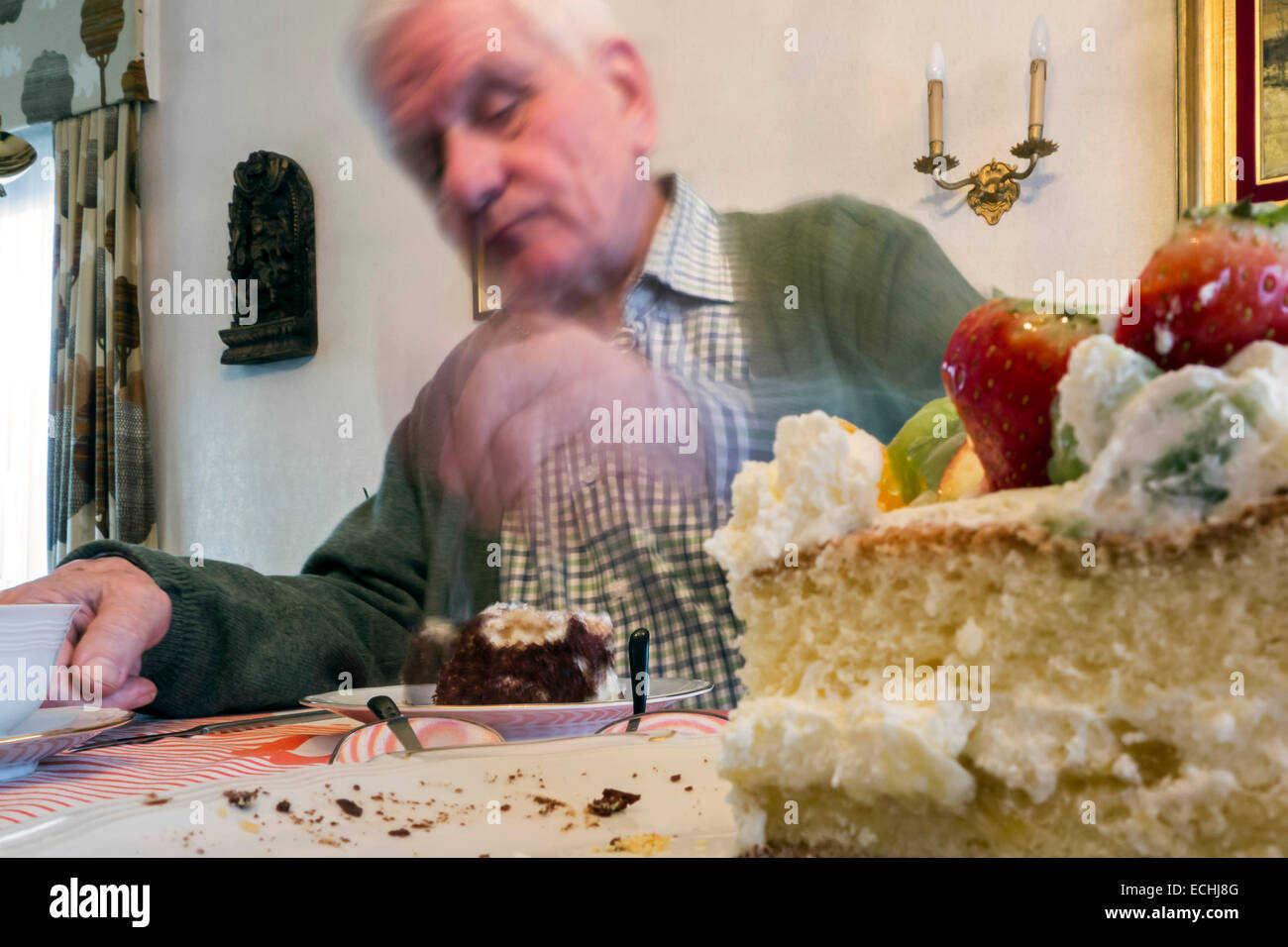 Triste guardando lonesome uomo anziano di mangiare la torta di compleanno a casa da sola in casa sua Foto Stock