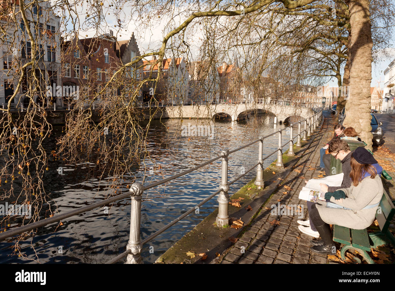 La gente seduta la lettura dal canale di Bruges, Belgio, Europa Foto Stock