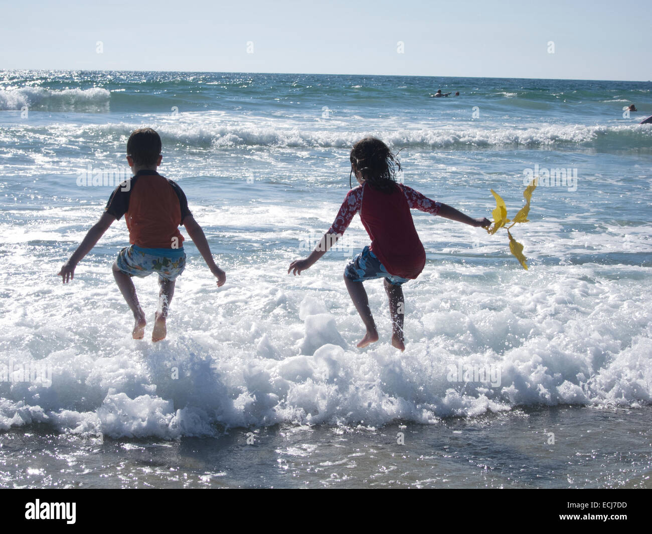 7-year-old twins godersi le onde durante la loro prima visita all'oceano. Foto Stock