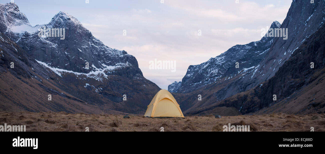 Tenda con panoramiche montagne sullo sfondo mentre il campeggio selvaggio a Horseid beach, Moskenesøy, Isole Lofoten in Norvegia Foto Stock