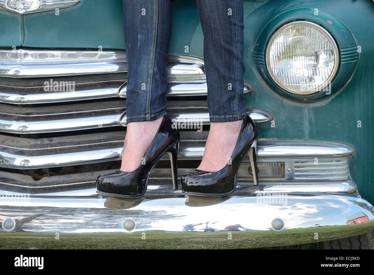 Donna in piedi i talloni in piedi sul paraurti di auto in sorelle, Oregon. Foto Stock