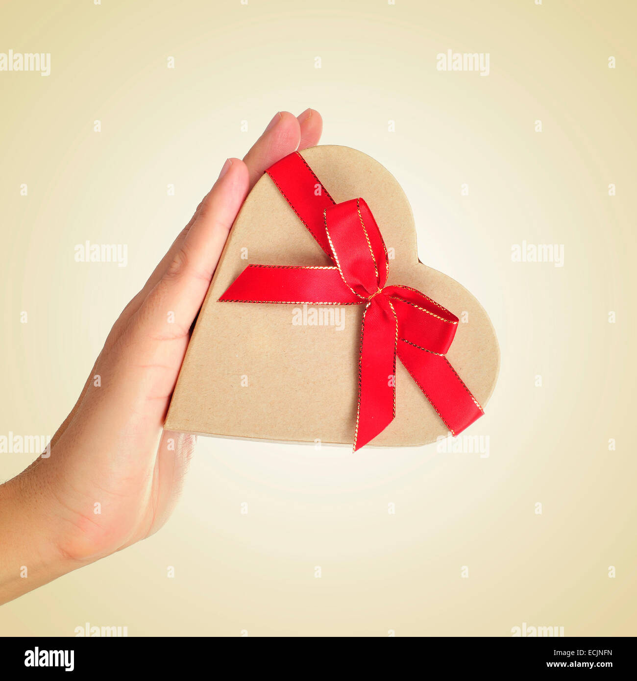 Un cuore a forma di scatola regalo legato con un nastro rosso nella mano di  un uomo Foto stock - Alamy