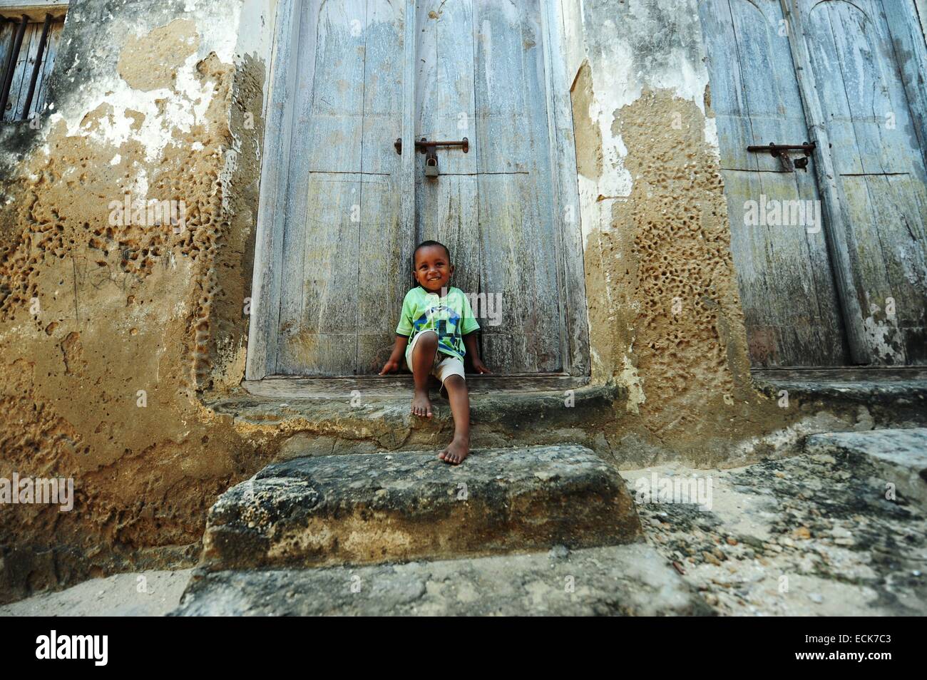 Il Kenya, l'arcipelago di Lamu, Lamu, un ragazzino di fronte a grandi porta coloniale Foto Stock