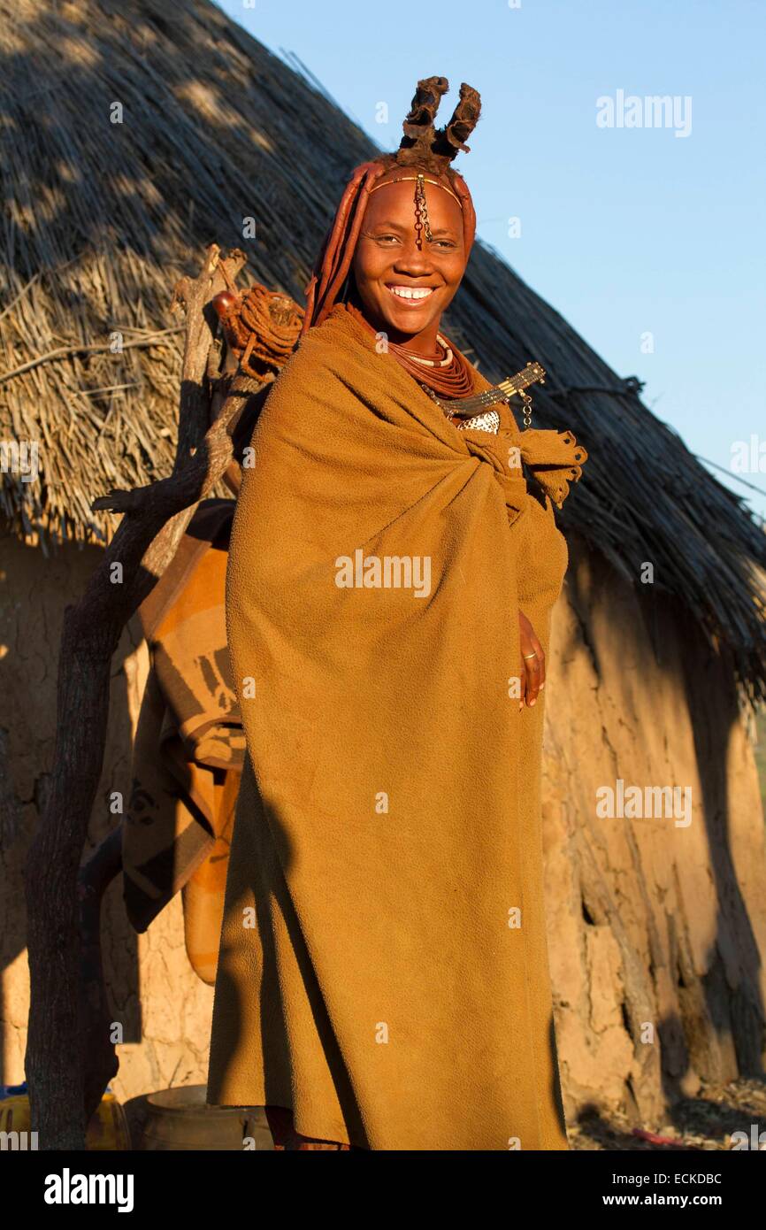 La Namibia, regione di Kunene, Kaokoland, Himba villaggio nei pressi di Opuwo, Himba donna di fronte a una capanna Foto Stock