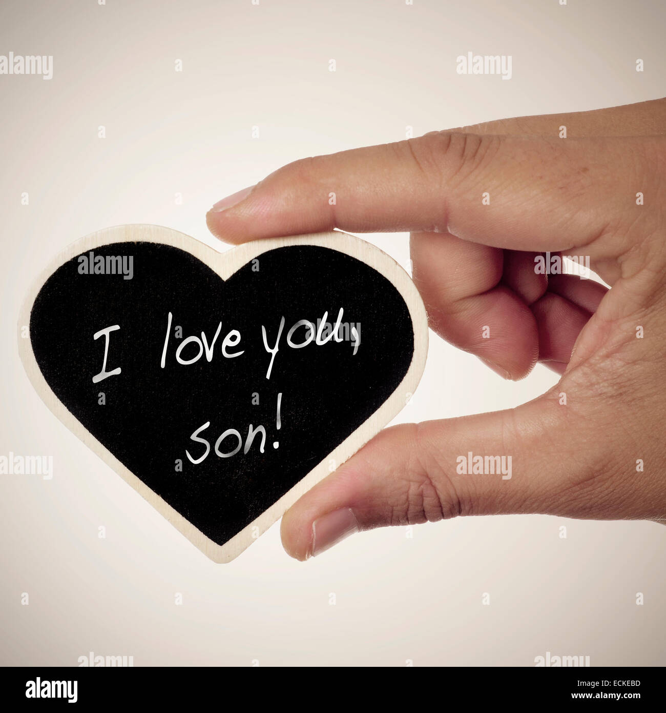 Un uomo con una a forma di cuore lavagna con la frase ti amo, figlio scritto in esso Foto Stock