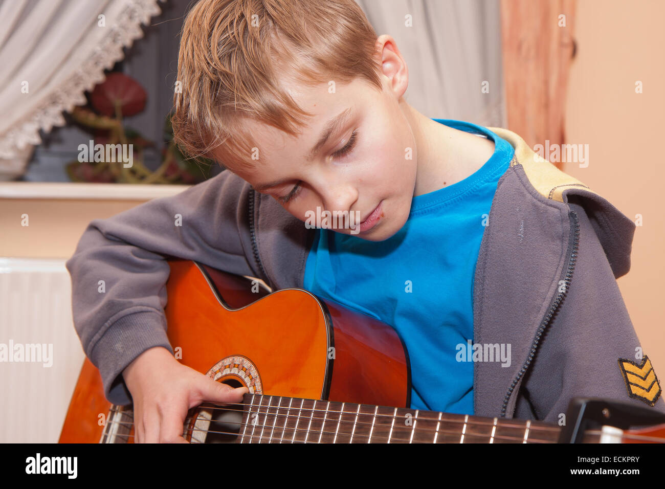 Un pelo biondo ragazzo di suonare una chitarra Foto Stock