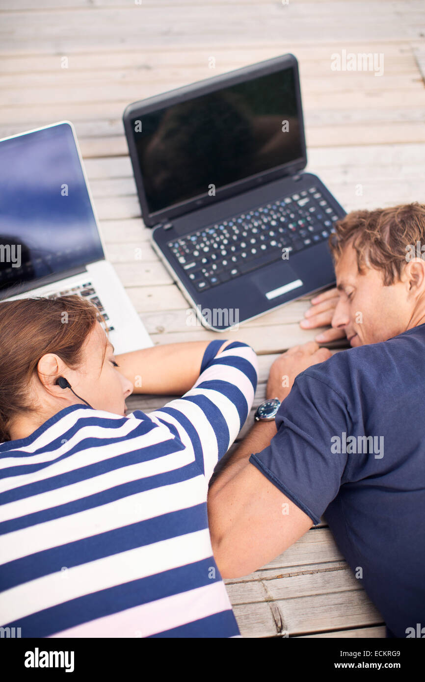 Angolo di Alta Vista della coppia matura dormire con i laptop sul molo Foto Stock