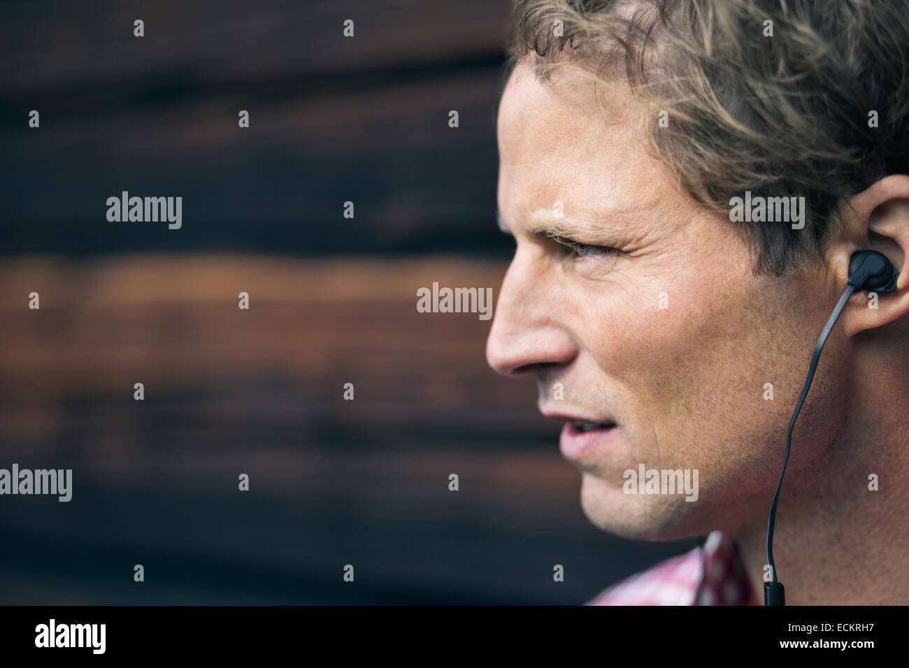 Uomo che indossa un dispositivo vivavoce esterno log cabin Foto Stock