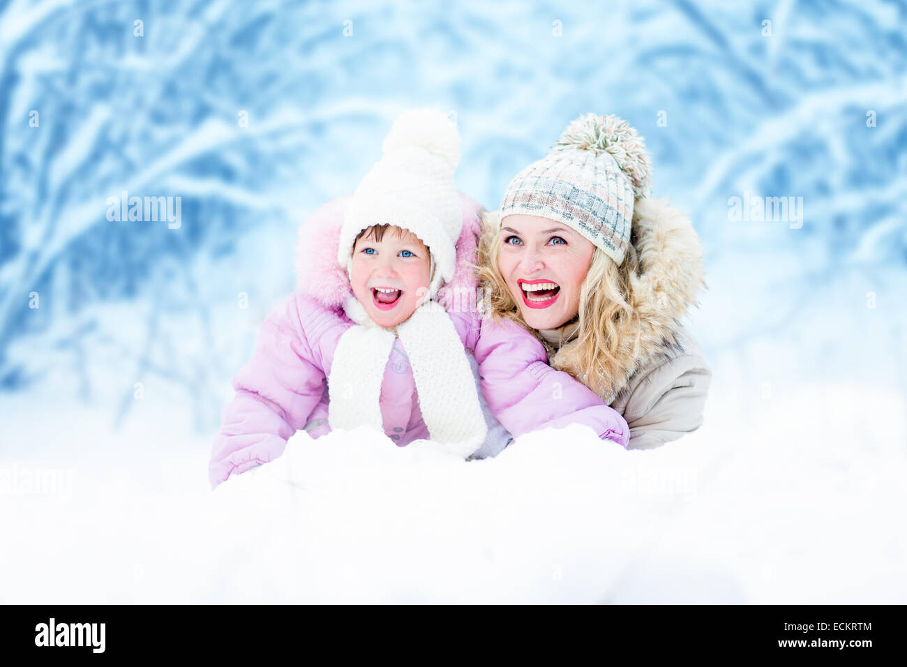 Felice madre genitore e bambino giacente nella neve outdoor Foto Stock
