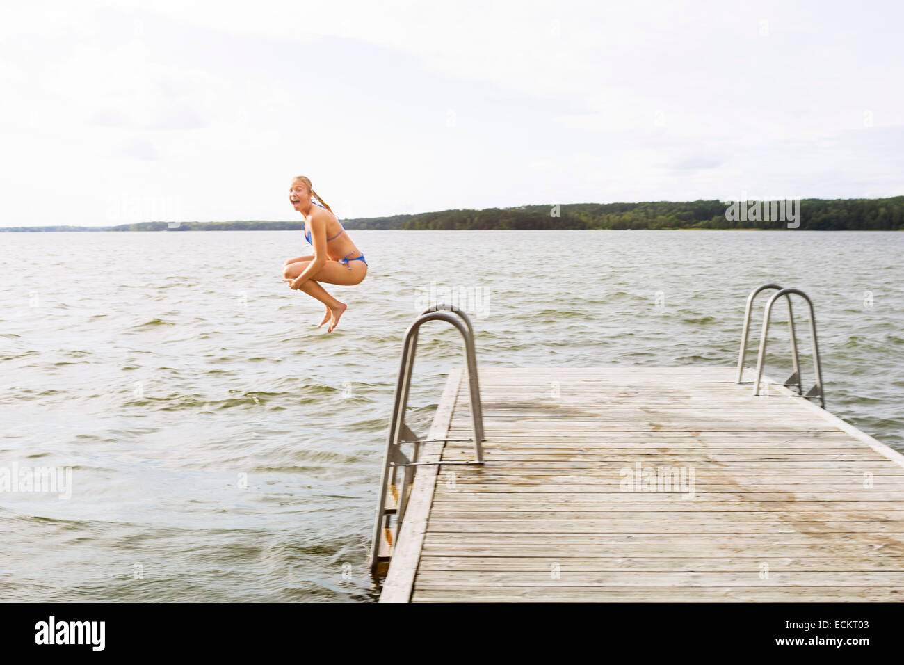Lunghezza piena vista laterale di Excited donna che si tuffa nel lago Foto Stock