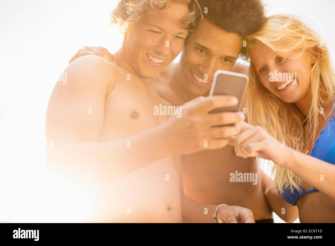 Happy amici utilizzando smart phone contro sky sulla giornata di sole Foto Stock