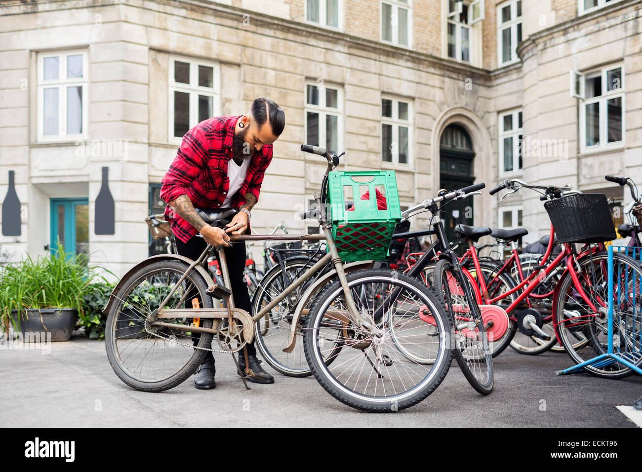 Proprietario bicicletta di bloccaggio presso il parcheggio al di fuori del negozio Foto Stock
