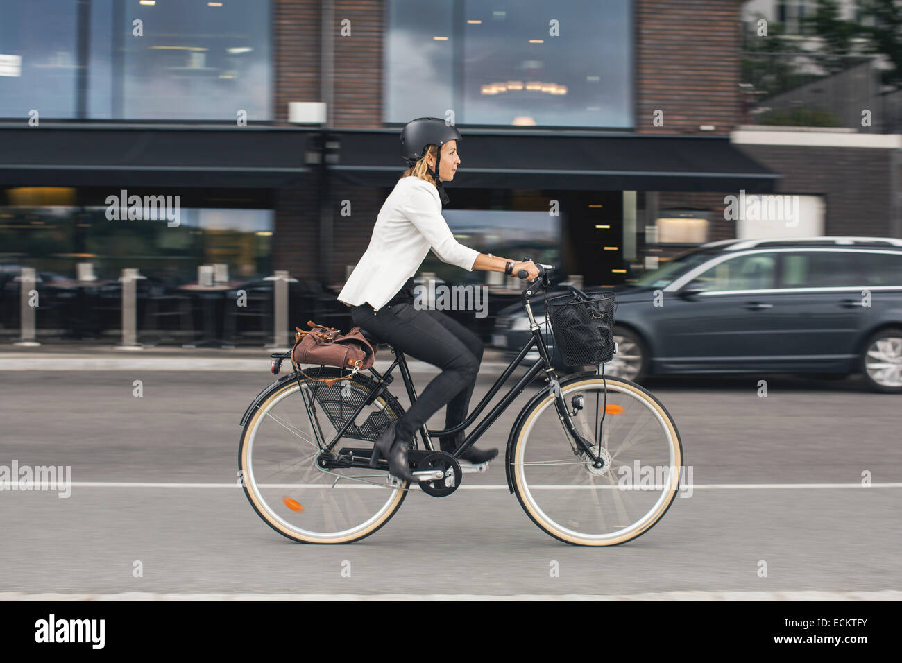 Lunghezza completa di imprenditrice equitazione Bicicletta su una strada di città Foto Stock