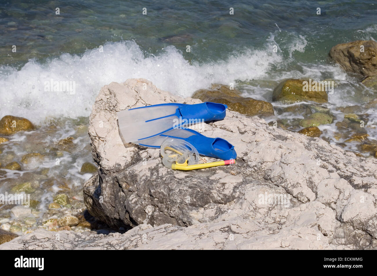 Pinne e maschera snorkel sulla roccia sulla riva del mare Foto Stock