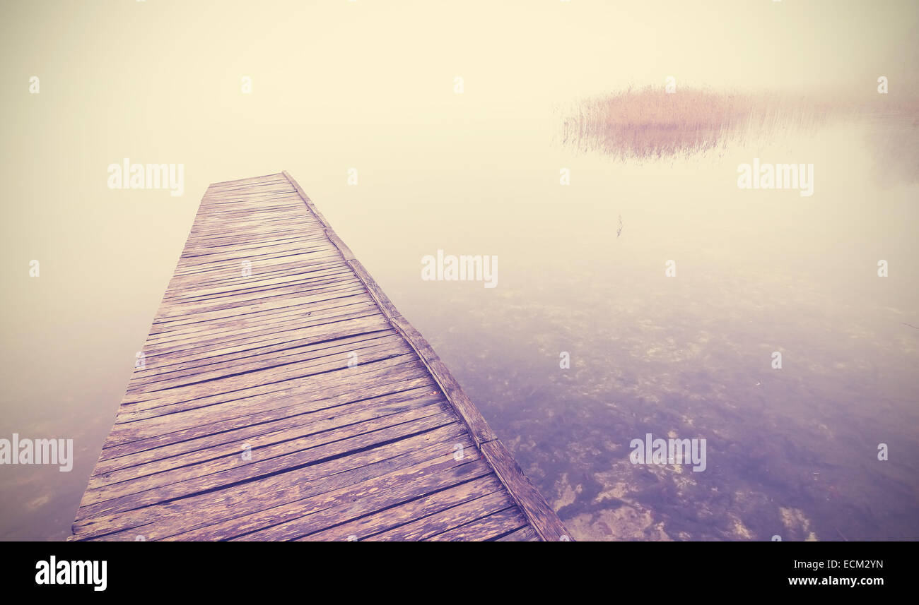 Retrò immagine filtrata del vecchio molo in legno in caso di nebbia fitta. Foto Stock