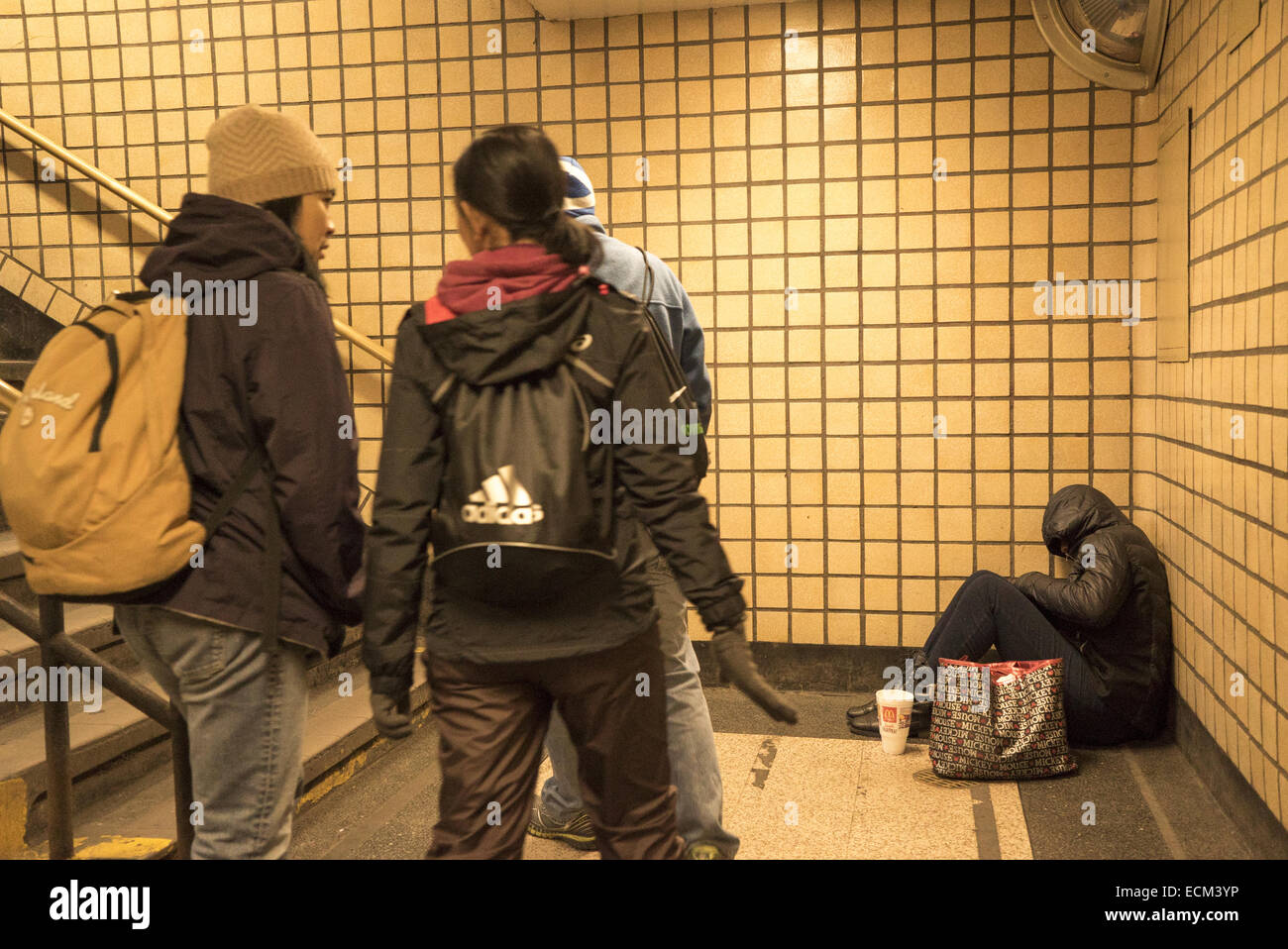 La donna siede chiedendo soldi all'ingresso di una stazione della metropolitana nel centro di Manhattan, New York. Foto Stock