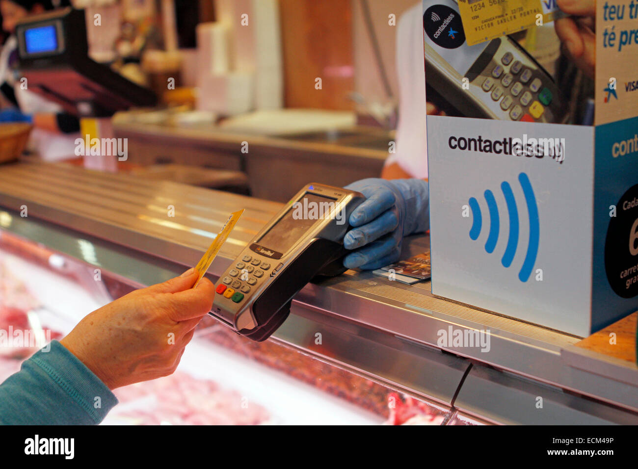 Una donna paga su una macelleria con un credito contactless card sistema nell'isola di Maiorca, SPAGNA Foto Stock