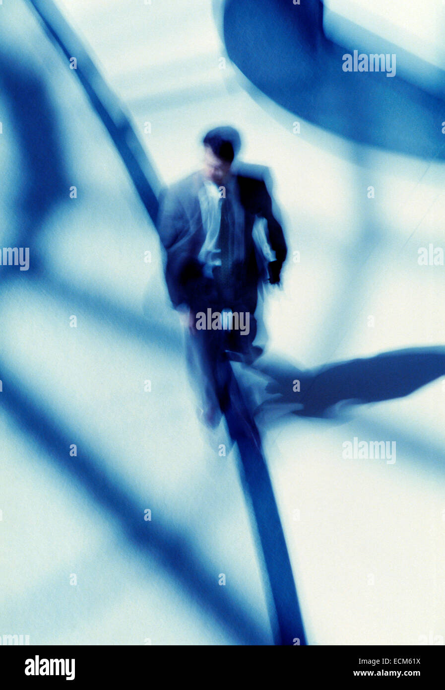 Business man in motion blur come egli cammina attraverso un luminoso atrio airport. Foto Stock