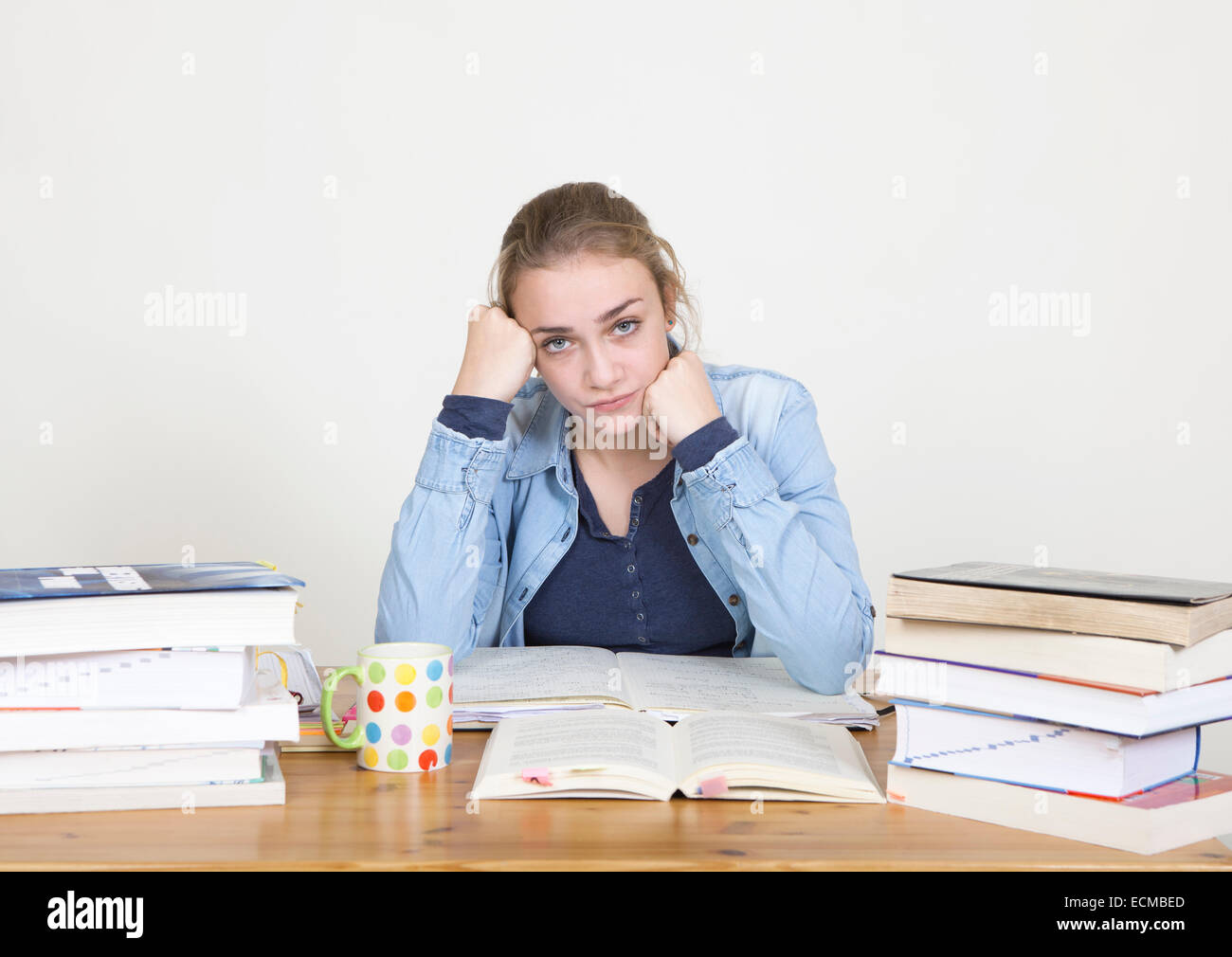 Uno studente con una pila di libri deve imparare per la scuola Foto Stock