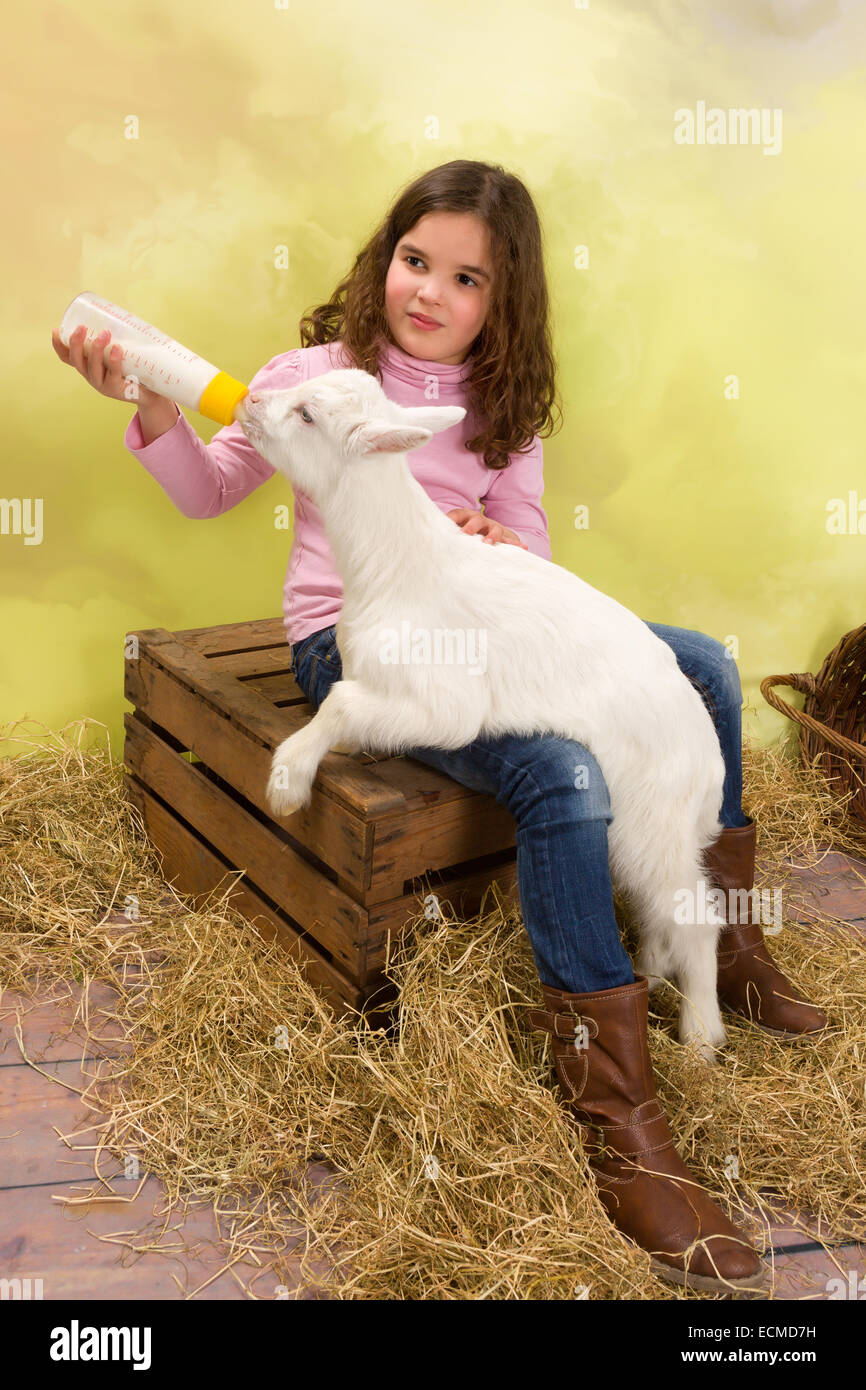 Bella ragazza alimentazione di un neonato Capra con una bottiglia di latte Foto Stock