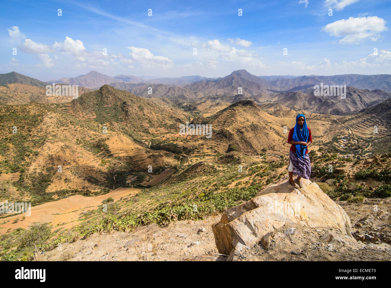 Local donna in piedi su una roccia di fronte a uno scenario di montagna lungo la strada che da Massaua a Asmarra, Eritrea Foto Stock