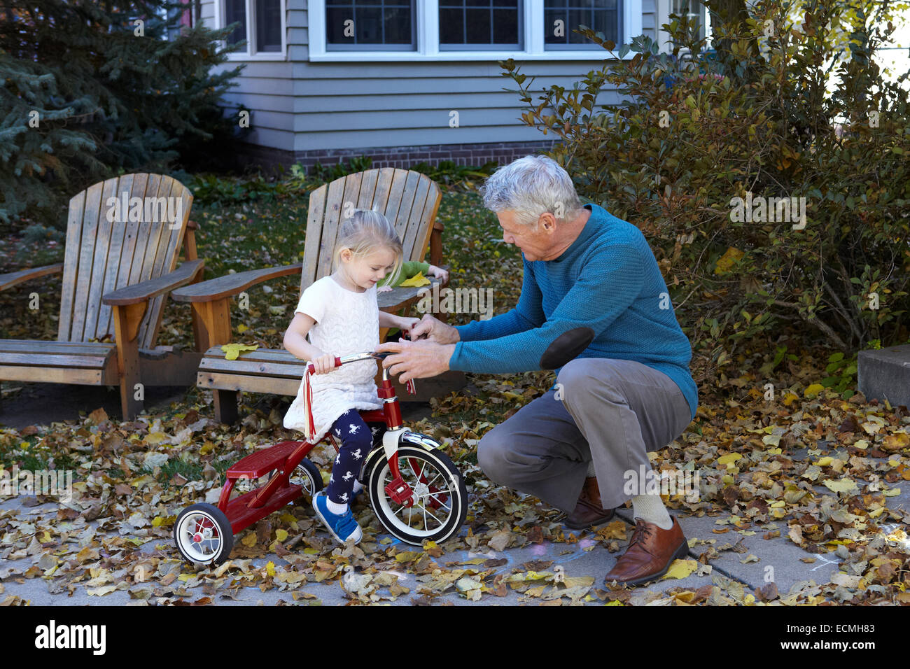 Nonno insegnamento sua nipote di cavalcare un triciclo Foto Stock