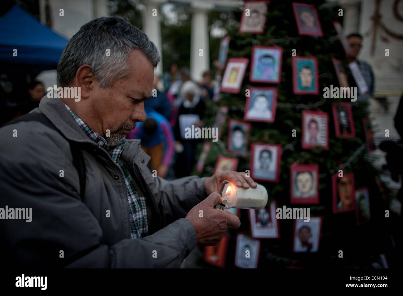 Città del Messico. Xvi Dec, 2014. Un uomo accende una candela durante l'installazione dell'albero "Verità, Giustizia e Pace per Ayotzinapa', che è decorato con i ritratti degli studenti mancante del normale scuola rurale di Ayotzinapa, a Città del Messico, capitale del Messico, del 16 dicembre, 2014. © Pedro Mera/Xinhua/Alamy Live News Foto Stock
