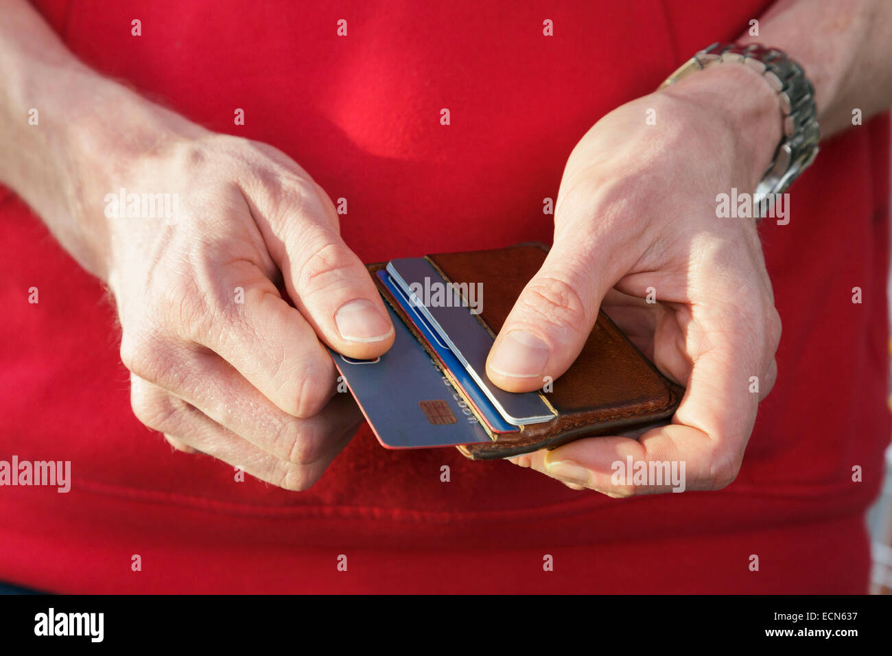Un uomo in rosso il ponticello rimozione di una carta di credito visa da un portafoglio per pagare un acquisto. Inghilterra, Regno Unito, Gran Bretagna Foto Stock