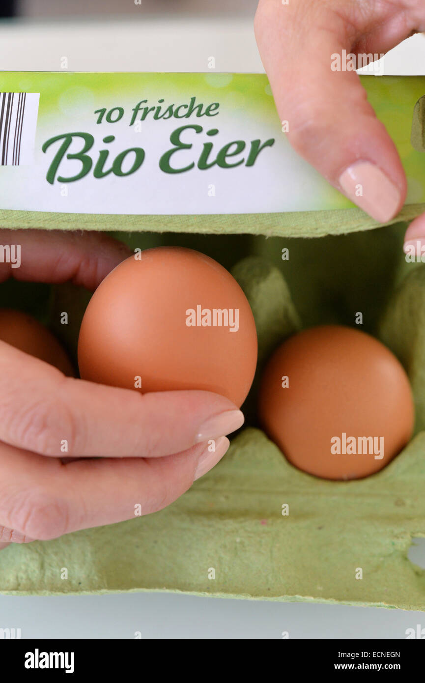 Una donna è il prelievo di un uovo da una scatola per uova dicendo 10 frische Eier Bio. Foto Stock