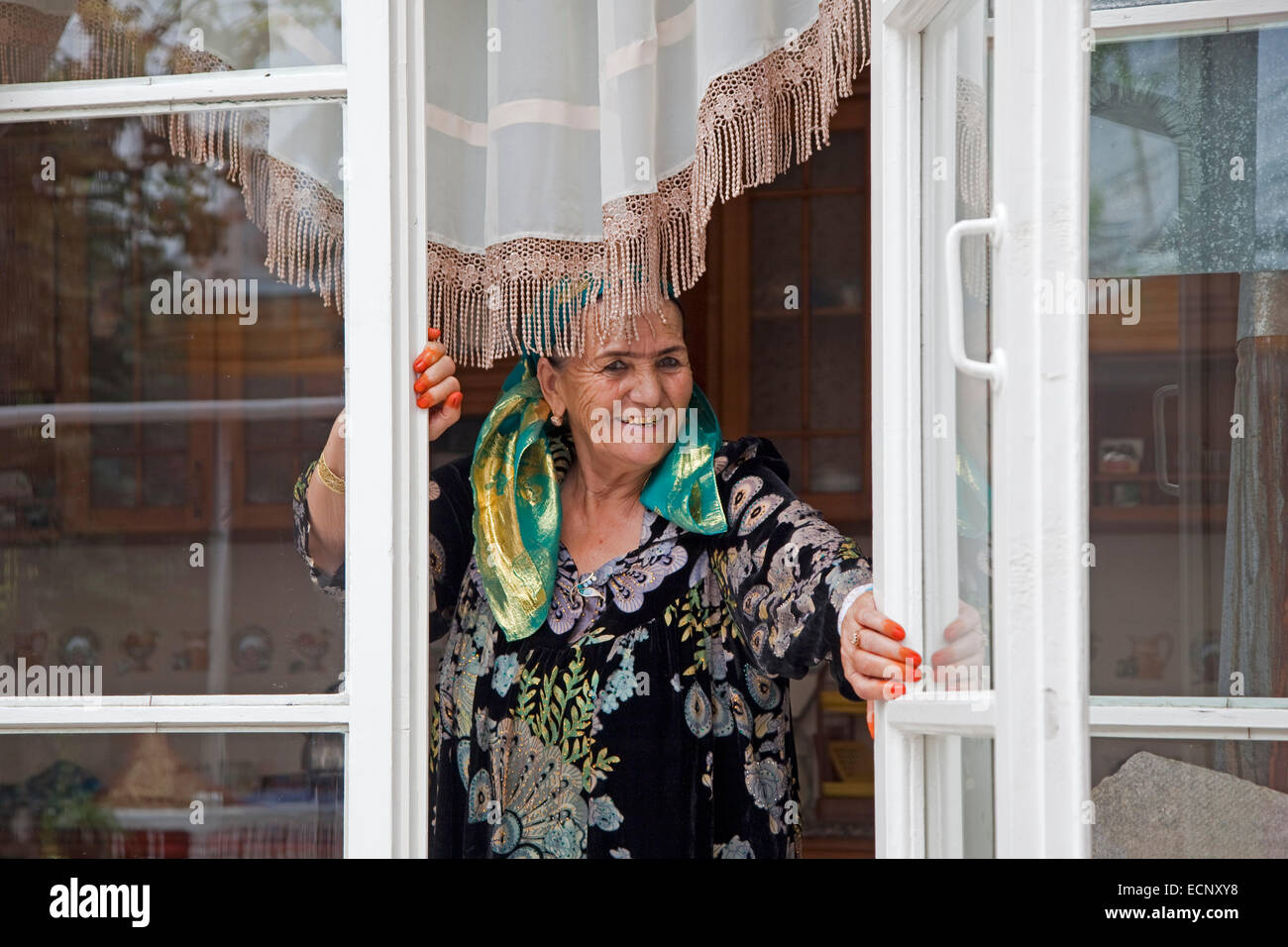 Sorridente Uzbek donna anziana che mostra i denti d oro e arancione punte del dito tinto con henna a casa, Samarcanda, Uzbekistan Foto Stock