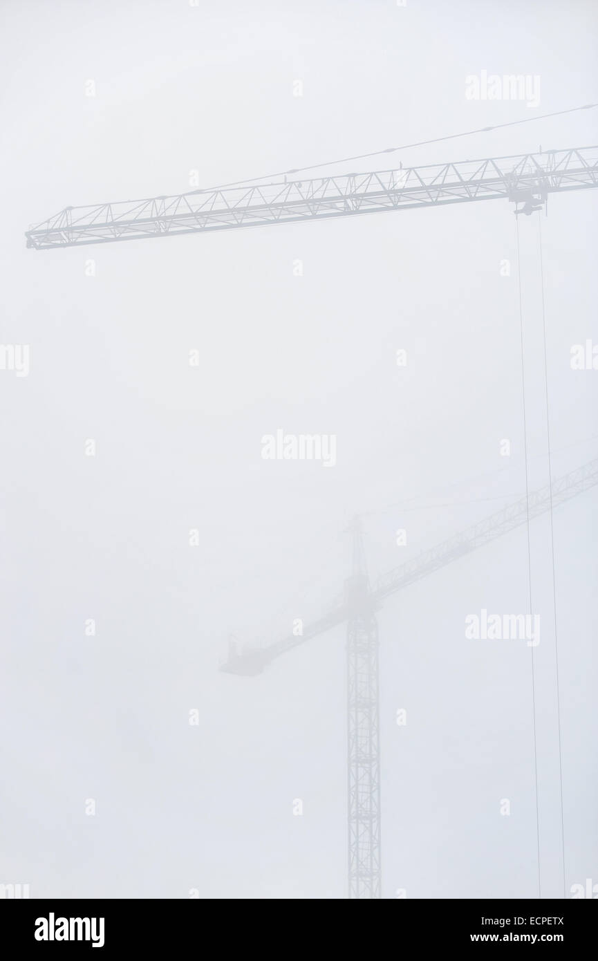 Ripresa industriale con gru da cantiere lavorano nella fitta nebbia Foto Stock