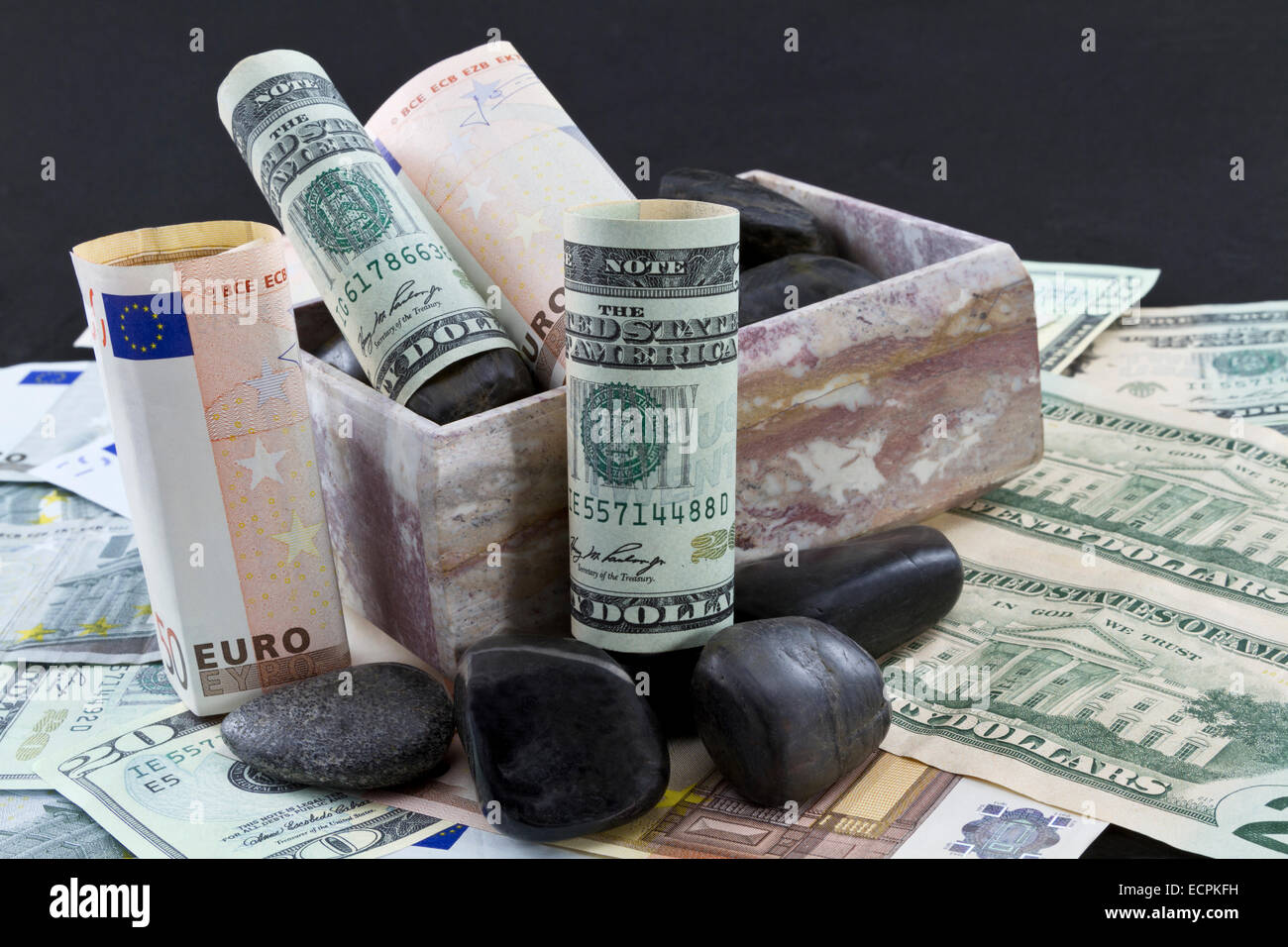 Unione di euro e dollari americani a sedersi su un letto di cambio entro una scatola di marmo accentati con rocce nere. Foto Stock